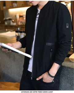 Detail view of a black bomber jacket with an arm patch and zipper pockets on a male model