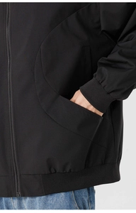 Gros plan de la veste de baseball noire avec poches incurvées et poignets élastiques