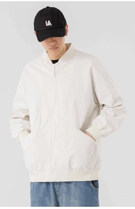 Détail du col baseball et des poches incurvées sur la veste de couleur blanc crème