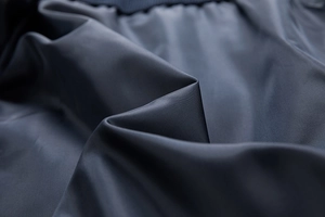 Macro shot of dark grey-blue smooth fabric lining with silky luster and fine texture