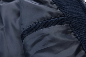 Detailed close-up of smooth navy blue lining and textured knit pocket edge on a cotton coat