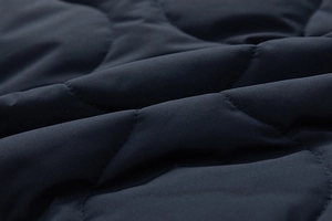 Close-up of men's padded cotton jacket featuring wave-pattern quilted fabric in navy blue