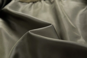 Detail of dark olive green synthetic fabric with smooth texture and high density weave