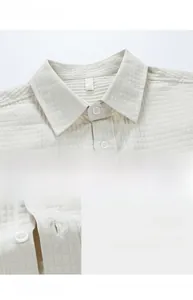 Detail of off-white waffle texture fabric with white resin buttons on men's shirt