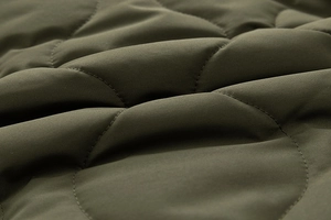 Detailed macro view of wave quilting on deep olive green matte fabric for men jacket