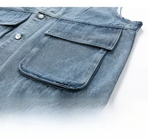 Detail of washed denim vest featuring large cargo pockets and branded metal buttons