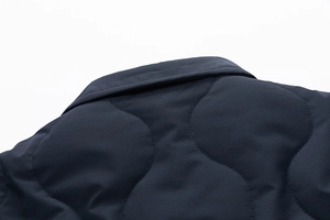 Detail of navy blue quilted cotton jacket showing wavy stitching and stand collar texture