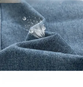 Macro shot of blue washed denim fabric texture with twill weaving detail and soft water drops