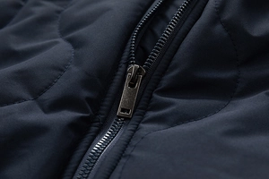 Close-up of a premium metal zipper and quilted fabric on a navy men's winter jacket