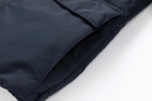 Detail of navy blue quilted jacket showing reinforced side pocket and windproof fabric