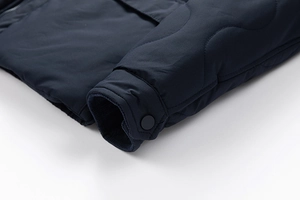 Detail of quilted navy jacket showing windproof ribbed cuffs and snap button closure