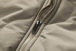 Close-up of khaki quilted cotton jacket with plastic zipper and wavy stitching detail