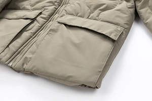 Detail of khaki quilted jacket featuring metal zipper and symmetrical cargo pockets