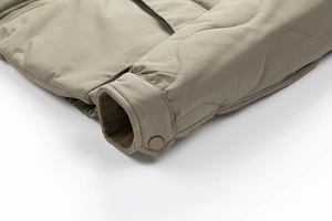 Detailed macro view of khaki quilted sleeve featuring ribbed windproof cuffs and snap button