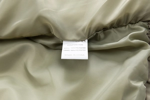 Detailed close-up of the olive green polyester lining and product label of a men's coat
