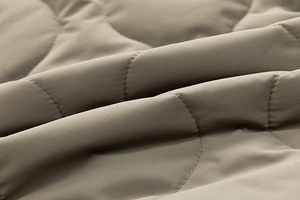 Macro shot of olive green quilted fabric detail with wavy stitching on casual cotton coat
