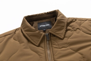 Detail of men's brown quilted jacket showing corduroy collar and wave stitch pattern