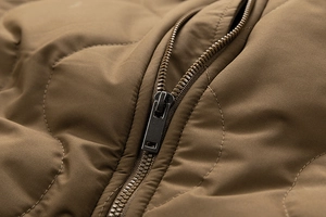 Detailed close-up of premium metal zipper and wave-quilted texture on casual brown cotton jacket