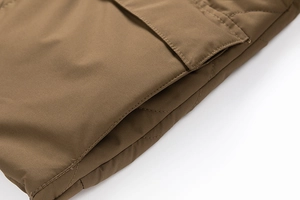 Detail view of khaki quilted jacket featuring functional cargo flap pocket and neat stitching