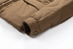 Detail of wave quilted brown cotton jacket showing ribbed cuffs and metal snap buttons