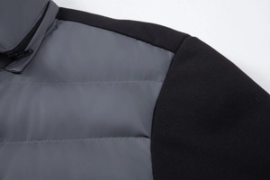 Detail of dark grey quilted fabric and black stitched shoulder on a men's winter jacket
