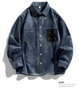 Détail d'une chemise en jean bleue avec la couture blanche à quatre coins sur la poche