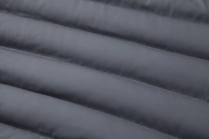 Close-up of dark grey hooded jacket showing horizontal quilted stitching and padded texture