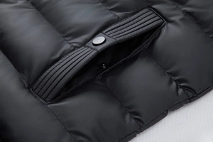 Close-up of quilted winter jacket pocket featuring metal snap button and ribbed trim detail
