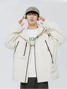 Gros plan sur une veste à capuche technique beige avec plusieurs poches zippées et cordons