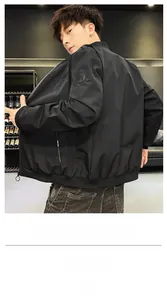 Detail of black bomber jacket sleeve featuring a round rubber badge and zip pocket