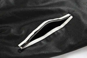 Macro shot of black textured leather jacket with contrast white piping and silver zipper