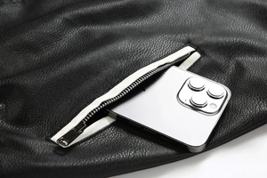 Detail of black pebbled faux leather jacket featuring a silver zipper and functional pocket