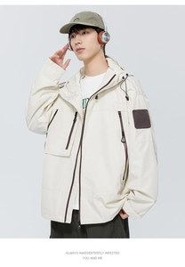 Détail de la veste à capuche beige clair avec fermeture éclair et écusson sur la manche