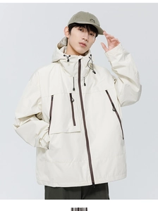 Détail d'une veste outdoor beige avec poches zippées contrastées et capuche protectrice