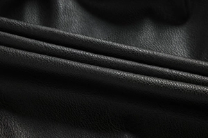 Macro detail of high-quality black faux leather with a premium lychee grain texture