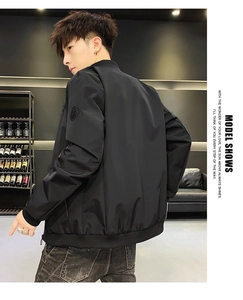 Rear view of black bomber jacket with ribbed cuffs and round sleeve patch detail