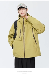 Détail d'une veste à capuche imperméable jaune moutarde avec poches zippées et ourlet
