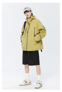 Détails d'une veste techwear imperméable jaune moutarde avec capuche et poches cargo