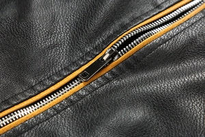 Close-up of black pebble leather jacket with contrasting ginger yellow metal zipper detail