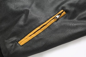 Detail of black lychee grain PU leather jacket with yellow contrast zipper piping