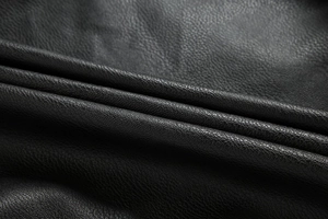 Close-up of black lychee grain PU leather texture on a sleek motorcycle jacket