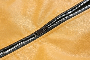 Close-up of yellow pebbled PU leather jacket with a high-quality black metal zipper