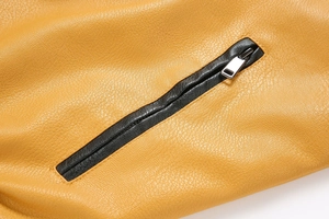 Macro shot of a black hidden zipper with silver metal puller on yellow PU leather jacket