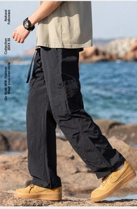 Detail view of black outdoor cargo pants with drawstring waist and large side pockets