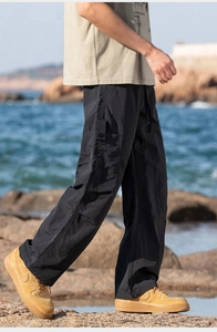 Detail of black outdoor cargo pants with large side pockets and adjustable drawstring waist