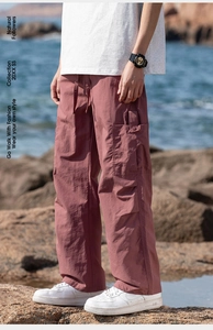 Outdoor shot of dark red cargo pants with large flap pockets and a wide-leg fit
