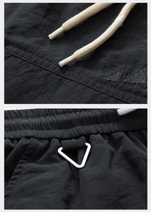 Detail of waterproof black cargo shorts featuring elastic waist, drawcord and metal triangle hook