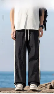 Dettaglio di pantaloni casual neri con strisce laterali bianche e coulisse regolabile in vita