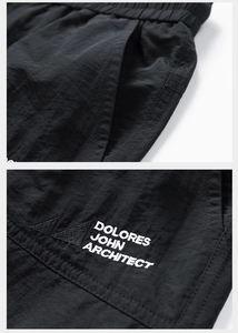 Detail of waterproof nylon shorts featuring elastic waist and Dolores John embroidery