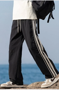 Dettaglio ravvicinato di pantaloni outdoor neri con strisce laterali e fettuccia con marchio